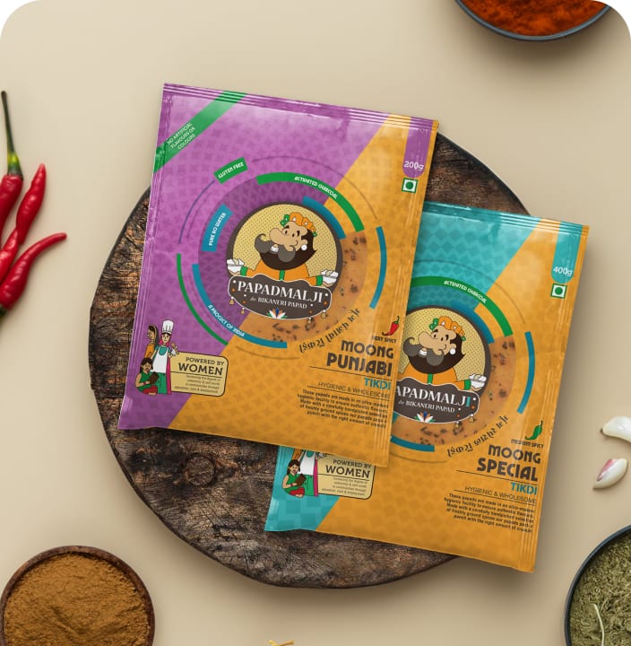 Papadmalji papad pouches on a wooden board surrounded by spices